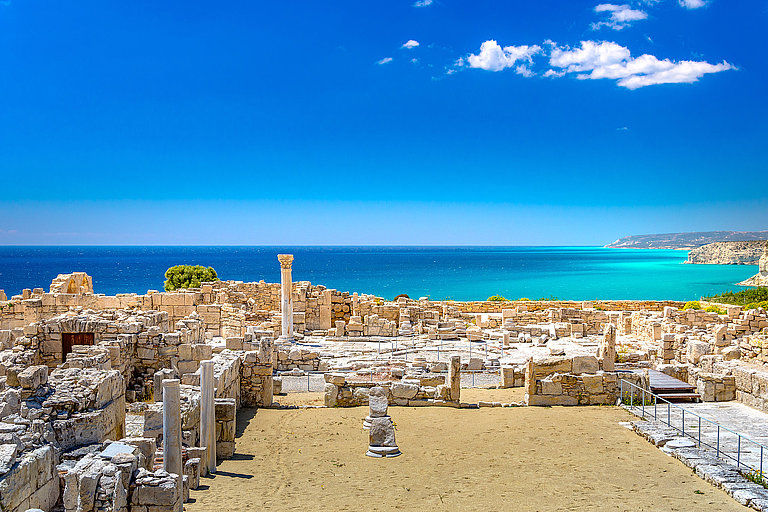 Blick über eine helle Küstenstadt mit Sandstrand und blauem Mittelmeer.