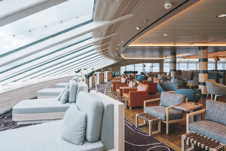 Blick auf einen Loungebereich eines Schiffes mit kleinen Betten und Sitzmöglichkeiten.