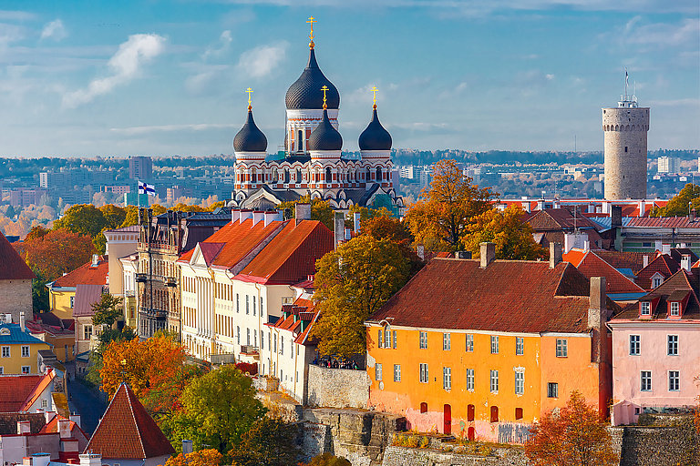 Blick über herbstliche Dächer auf eine Kirche mit Zwiebeltürmen in der Altstadt.