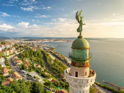Freiheitsstaute von Triest mit Blick auf Stadt, Meer und Küste im Abendlicht.
