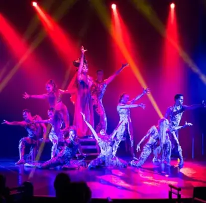 Bunte Bühnenshow mit ArtistInnen unter roten und blauen Scheinwerfern im Theater an Bord.