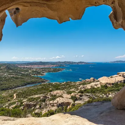 Blick durch eine Felsöffnung auf die Küste und das blaue Meer Sardiniens.