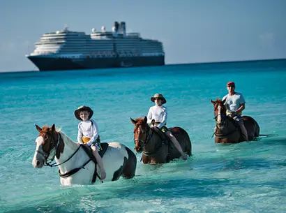 ReiterInnen auf Pferden im türkisblauen Wasser vor Kreuzfahrtschiff und weitem Horizont.