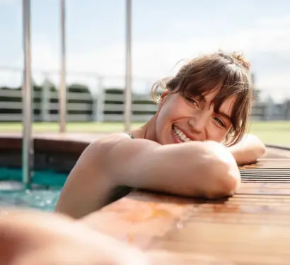 Eine lächelnde Frau lehnt entspannt am Rand eines Pools auf dem Außendeck eines Flussschiffs.