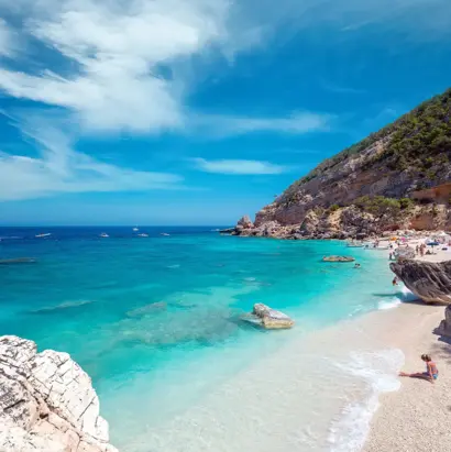 Heller Kiesstrand mit türkisblauem Meer und steiler Felsküste in Süditalien.