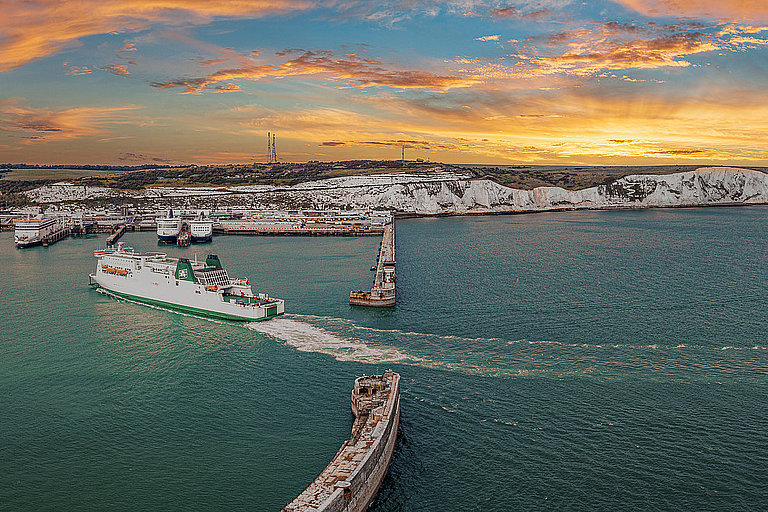 Küstenstadt bei Sonnenuntergang mit Promenade, Hafen und ruhigem Meer im Panorama.