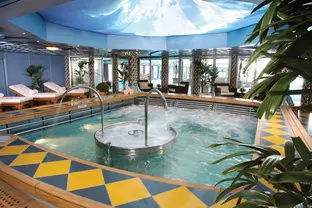 Helle Whirlpoolanlage im Spa an Bord mit Liegen, Pflanzen und Panoramafenstern.