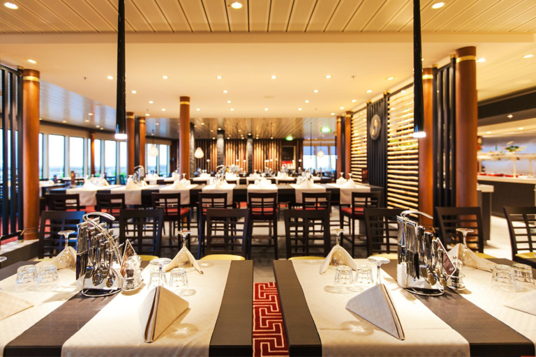 Elegantes Restaurant mit gedeckten Tischen, warmem Licht und Panoramafenstern.