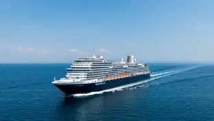 Kreuzfahrtschiff fährt auf offenem Meer unter blauem Himmel weg vom Horizont.