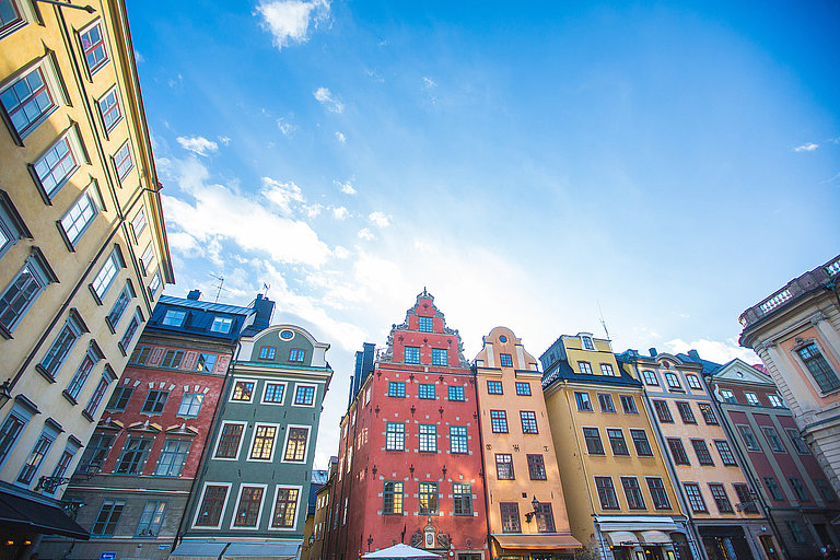 Bunte historische Fassaden in einer Altstadt mit blauem Himmel und Sonnenschein.