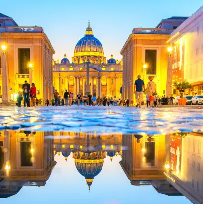 Petersdom in Rom bei Abendlicht mit Spiegelung auf der Via della Conciliazione.