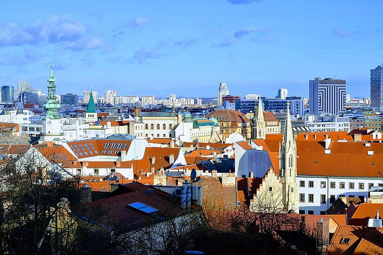 Panoramablick auf Dächer, Türme und moderne Gebäude einer Stadt bei Tageslicht.