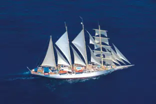 Panoramablick auf ein Segelschiff im tiefblauen Ozean unter sommerlichem Himmel.