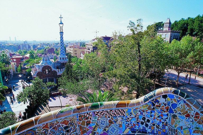 Panoramablick auf Barcelona mit grüner Landschaft und hellem Licht im Vordergrund.