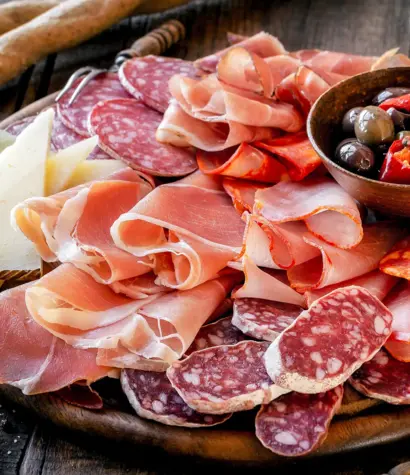 Cures meat platter with cheese and spicy olives served as tradit Spanische Tapas mit Schinken, Käse, Oliven und Brot auf rustikalem Teller.