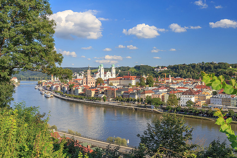 Panoramablick über Passau mit Donau, historischer Altstadt und grünen Hügeln.