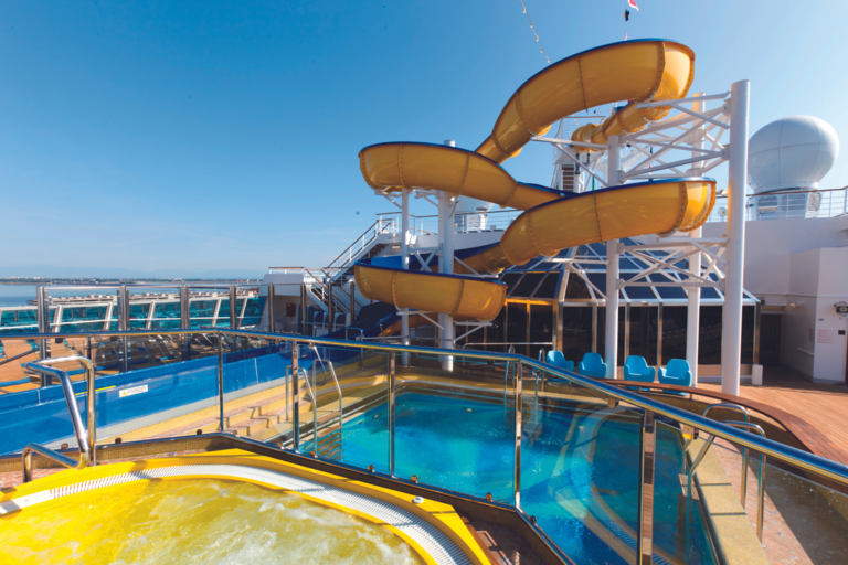 Das Bild zeigt eine Poolanlage mit Rutschen und Liegen auf dem Deck eines Schiffs.