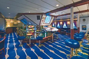 Moderne Bar mit blauen Akzenten, Barhockern, Stehtischen und mehreren Fenstern.
