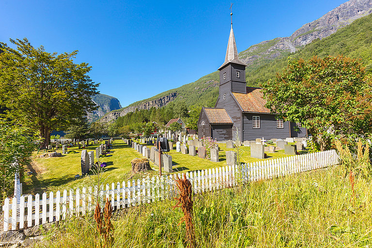 Alpines Dorf mit Kirche, Bergkulisse und Blumenwiese im sonnigen Salzkammergut.