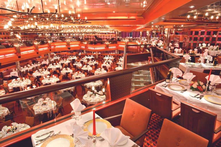 Modernes, beleuchtetes Restaurant mit orangenen Akzenten auf zwei Etagen aufgeteilt.