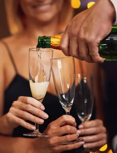 Feiernde Menschen stoßen mit Sektgläsern an, elegantes Ambiente und festliche Stimmung.