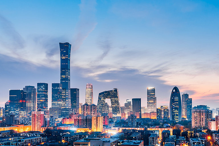 Moderne Skyline von Peking, bei Abenddämmerung mit beleuchteten Hochhäusern und Stadtlichtern.