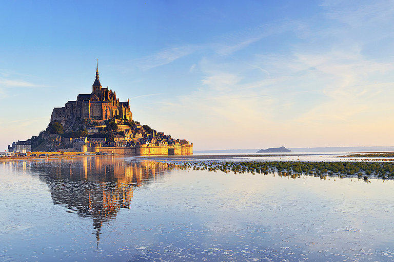 Dawn at Mont Saint Michel. France Mont Saint-Michel spiegelt sich im nassen Sand unter klarem Himmel bei Ebbe.