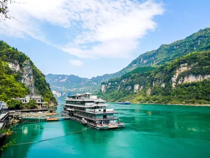 Bootsanleger am Yangtze in China mit türkisfarbenem Fluss und grünen Felsbergen.