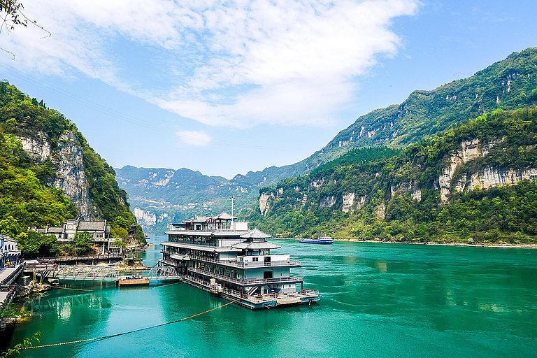 Bootsanleger am Yangtze in China mit türkisfarbenem Fluss und grünen Felsbergen.