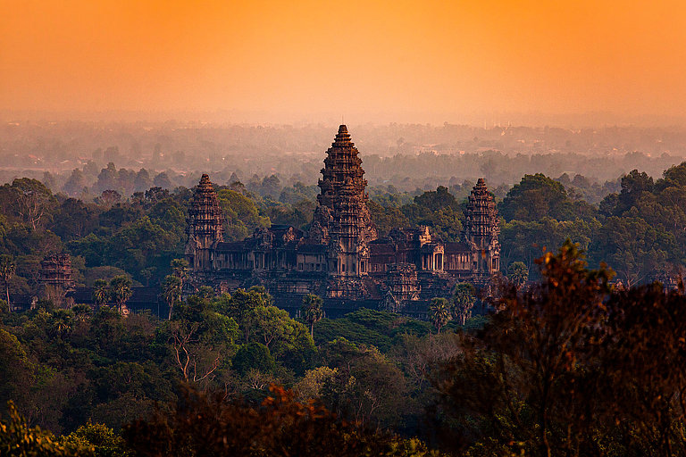 Tempelturm ragt aus dichtem Dschungel von Angkor im warmen Abendlicht hervor.