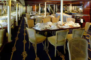 Altmodisches, hölzernes Restaurant mit älteren Tischen und Stühlen auf einem Kreuzfahrtschiff.