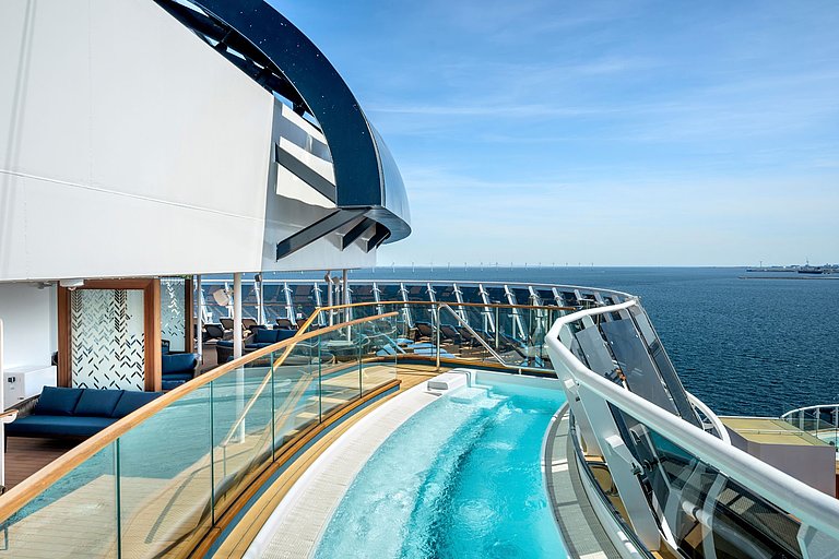 Kleines, längliches Pool auf dem Außendeck eines Kreuzfahrtschiffs mit blauem Meerblick.