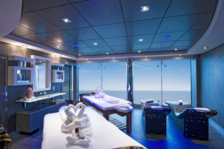 Heller Wellnessbereich an Bord mit Massageliegen und Panoramablick aufs dunkelblaue Meer.