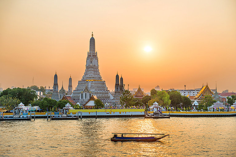 Leuchtender Tempel a Fluss bei Sonnenuntergang mit Boot auf goldenem Wasser.