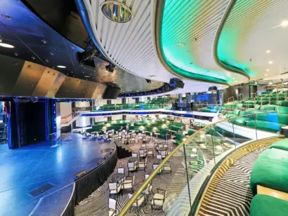 Großes Schiffstheater mit Bühne, grünen Sitzreihen und geschwungener Lichtdecke.