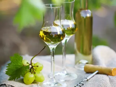 Olivenöl in Glasflasche und Schale mit Oliven auf rustikalem Holztisch.
