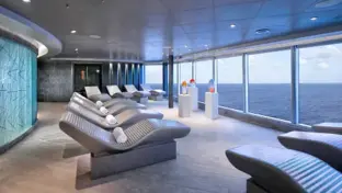 Wellnessbereich an Bord mit Liegen, Panoramafenstern und weitem Blick aufs Meer.