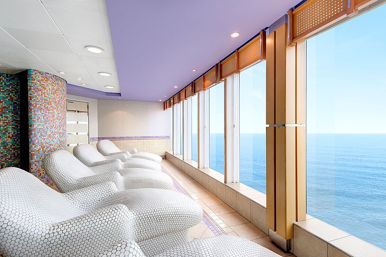Moderner Spabereich eines Kreuzfahrtschiffs mit Spaliegen und Ausblick auf das Meer.