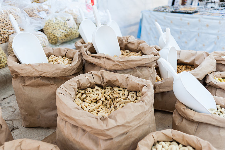 Taralli - traditional Italian snack food typical of Apulia Stoffsäcke mit verschiedenen Nudelsorten und Körnern auf einem Marktstand im Freien.