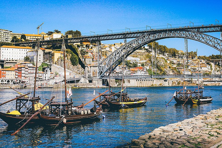 Boote am Ufer des Douro mit Blick auf Portos Altstadt und sonnige Häuser.