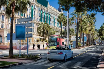 Weißes Auto fährt auf der La Croisette, dem Strandboulevard in Cannes.