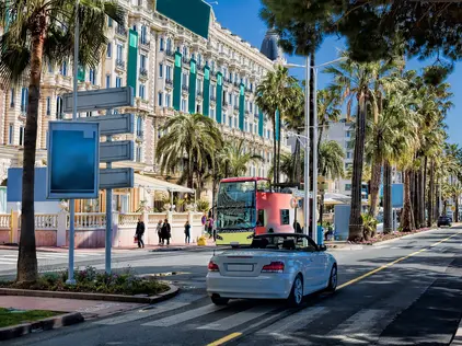 Weißes Auto fährt auf der La Croisette, dem Strandboulevard in Cannes.