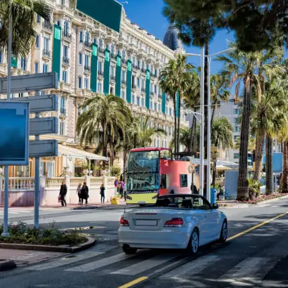 Weißes Auto fährt auf der La Croisette, dem Strandboulevard in Cannes.