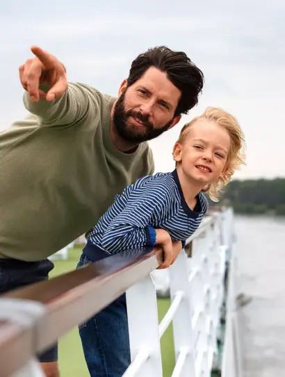 Das Bild zeigt einen Vater und sein Kind auf dem Deck eines Flusskreuzfahrtschiffes. 
