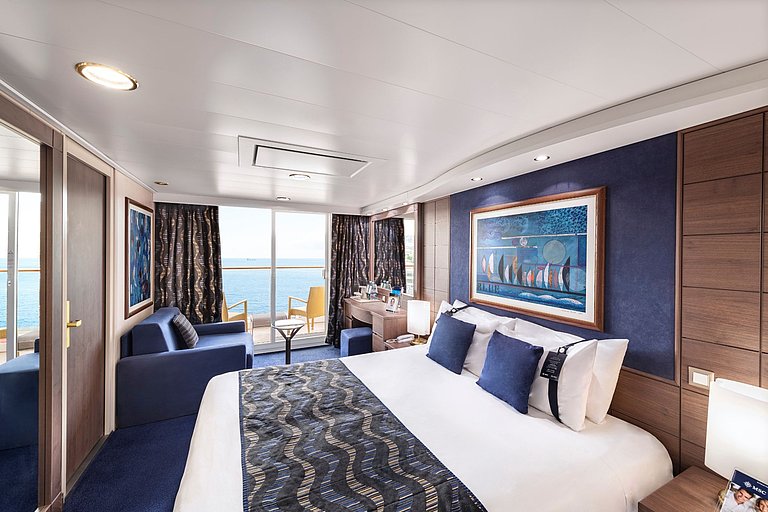 Elegante Schiffskabine mit Doppelbett, Sofa, großem Balkonausgang und Meerblick.