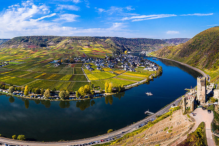 Panoramablick auf Flussschleife, Stadt und grüne Hügel unter blauem Himmel.