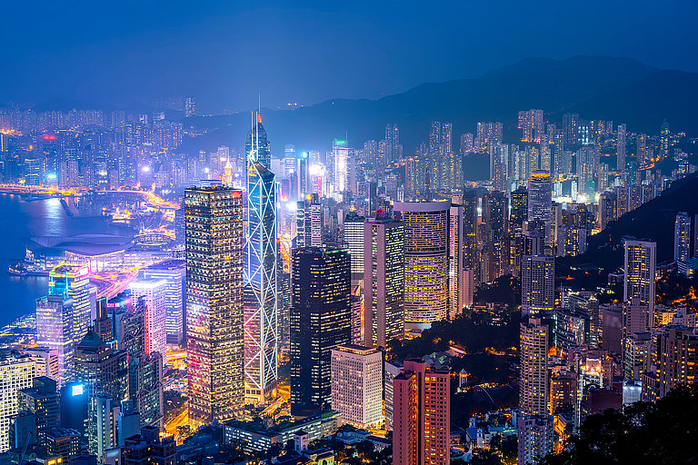 Nächtliche Skyline mit leuchtenden Hochhäusern und bunten Lichtern der Großstadt, Hongkong.