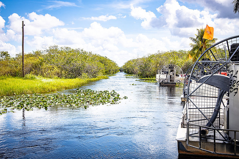 Boote fahren durch die Everglades in Florida, umgeben von Wasser und dichter Natur.